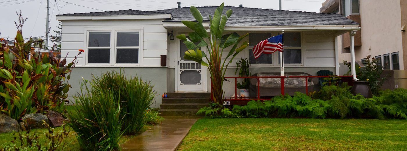 American flag on the porch of a single-story California bungalow