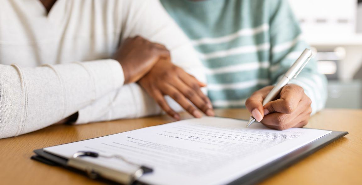 One hand resting on another as a loan document is signed
