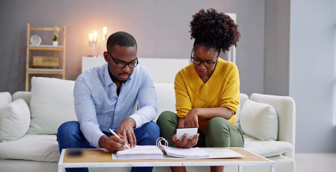 A couple working through a household budget with a ledger and calculator